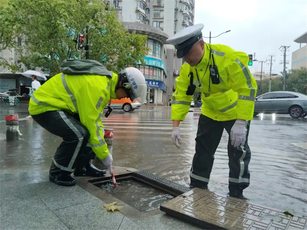 四大隊民警蘇張靈、輔警王志斌在牡丹江路寶林路積水點對下水道進行清理。